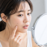 顔のほくろを鏡で確認する女性